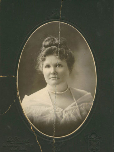 damaged portrait of a woman in the early 1900's wearing pearls with a crack going down the middle.